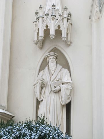 Kirche, Sandsteinfigur Johannes Calvins am Portal